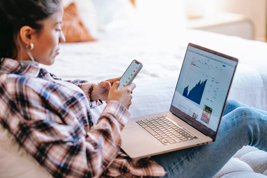 Vrouw kijkt op mobiel achter laptop